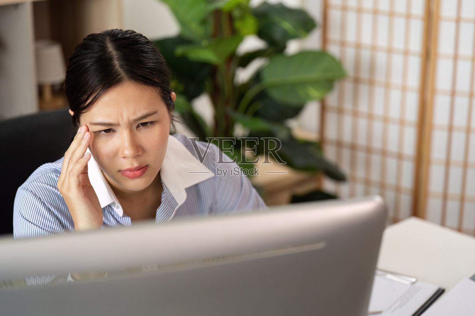 办公室综合症：年轻女性不适地眯着眼睛看电脑屏幕照片摄影图片