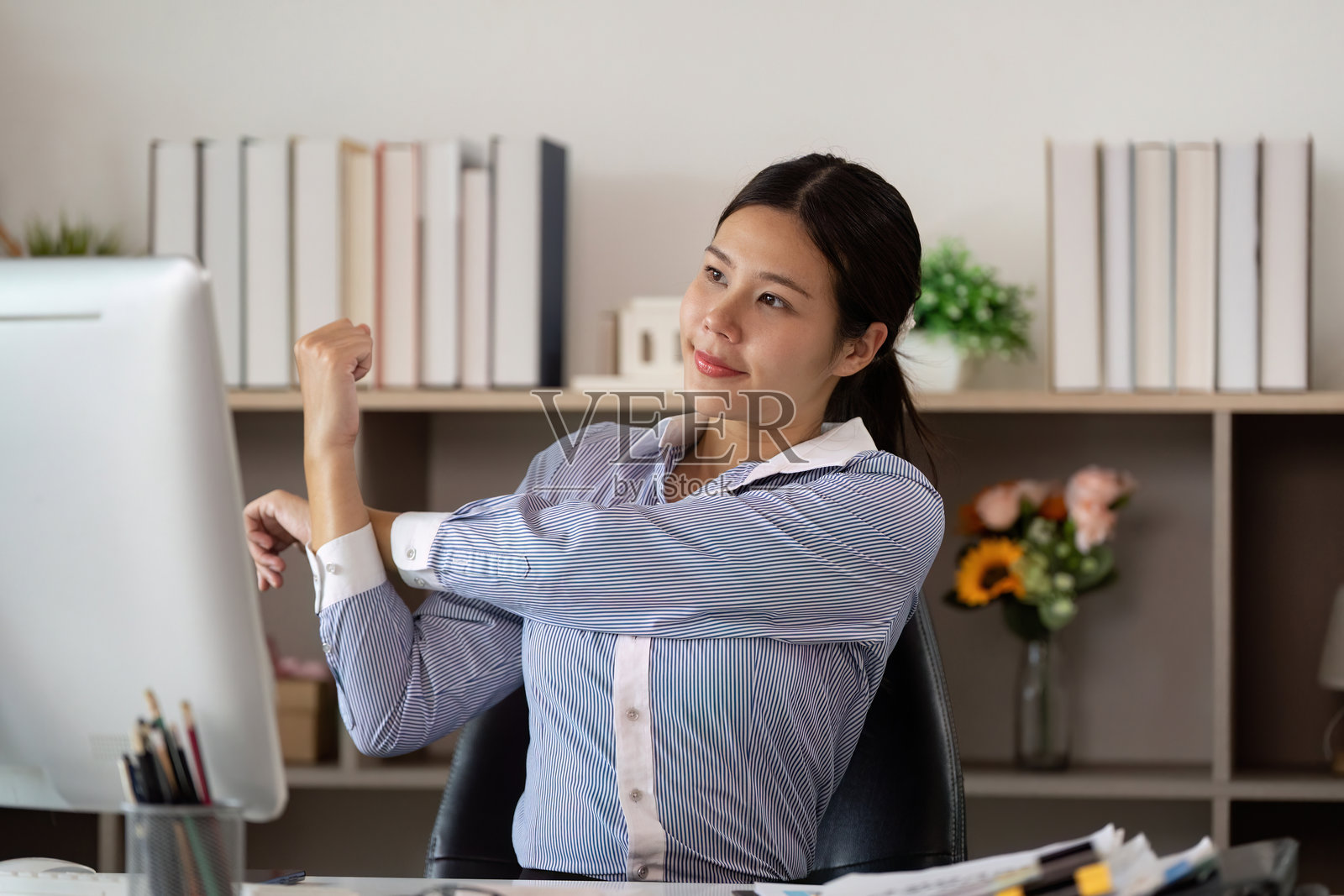 办公室综合症：年轻女性在工作站进行手臂伸展照片摄影图片