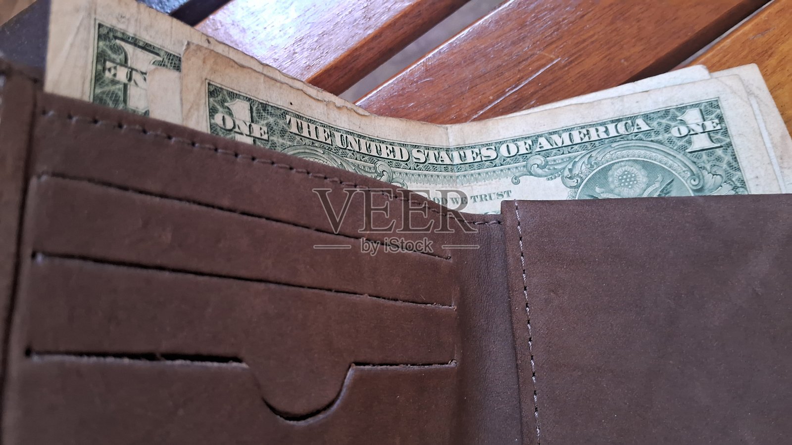 皮革钱包里的美元钞票放在木质背景上照片摄影图片