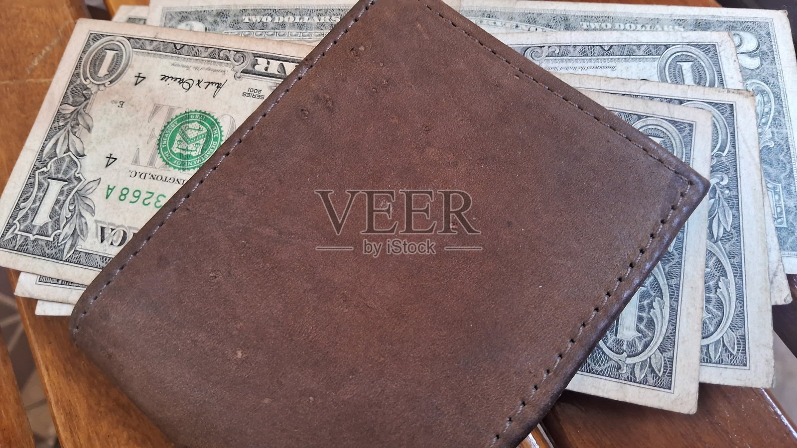 皮革钱包里的美元钞票放在木质背景上照片摄影图片