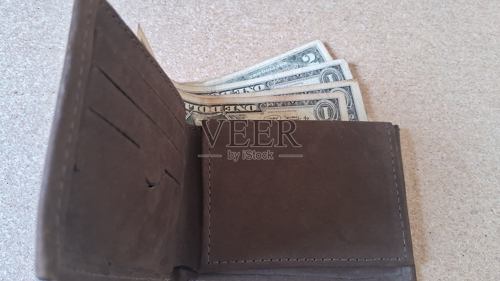 皮革钱包里的美元钞票放在木质背景上照片摄影图片