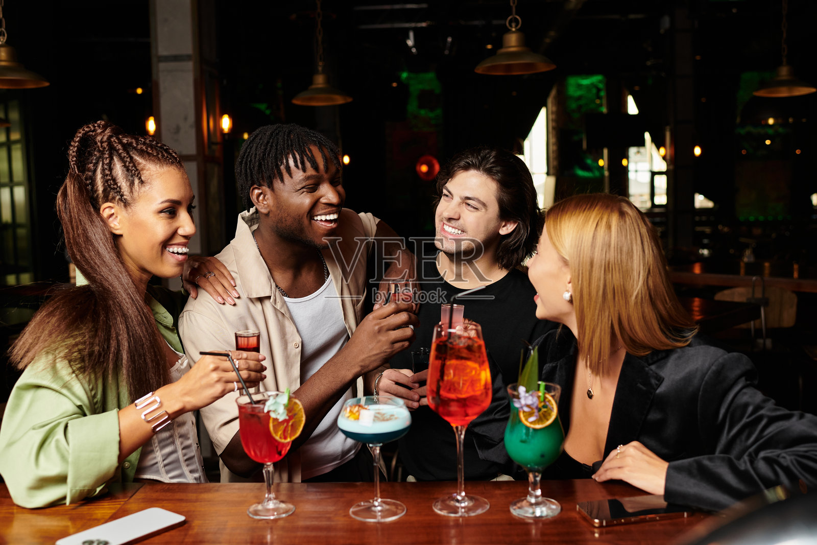 年轻同事们在热闹的公司派对上庆祝，手中举着五彩缤纷的饮料，欢声笑语不断。照片摄影图片