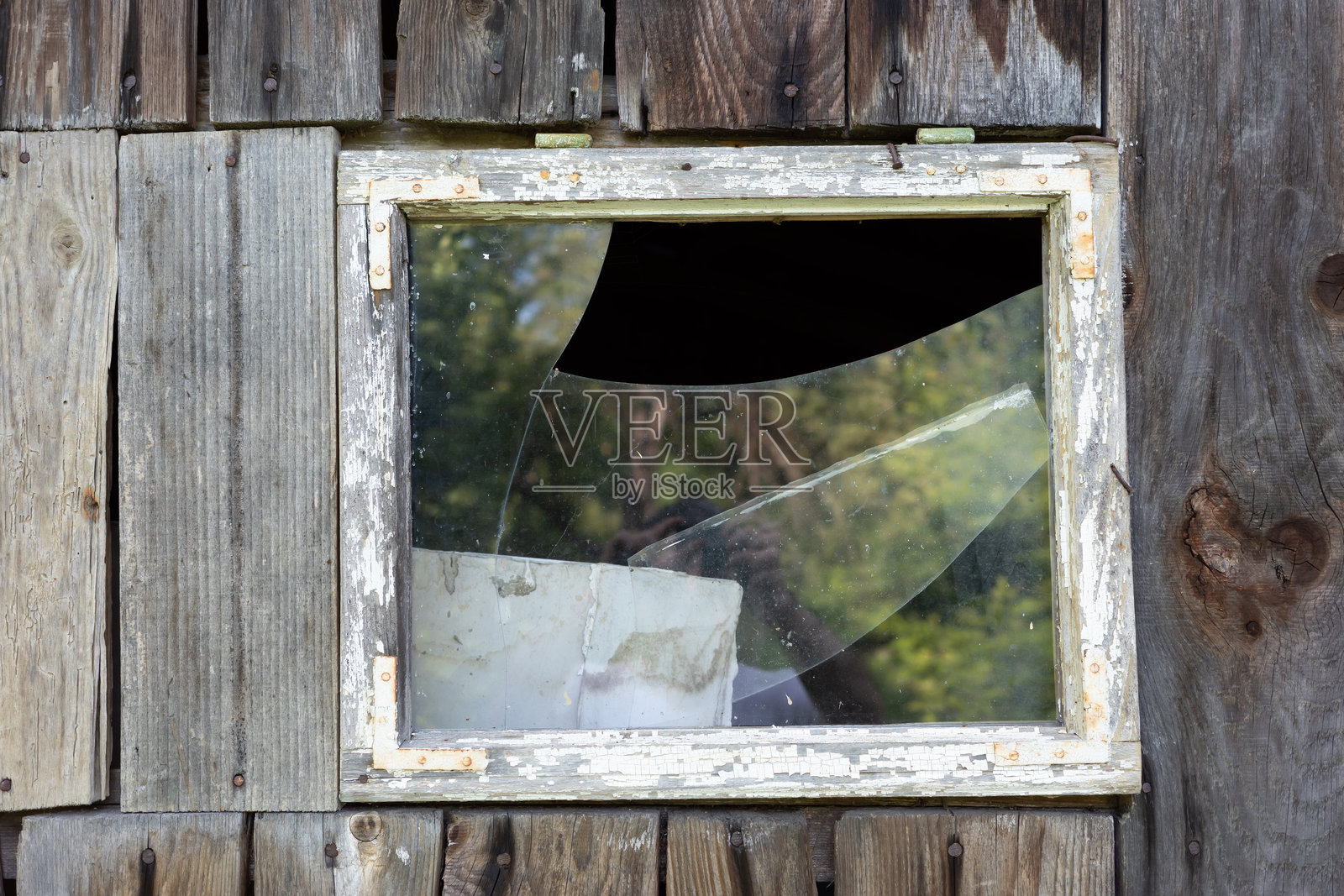 破碎窗户的特写，展示了其老旧的窗框和破碎的玻璃。照片摄影图片