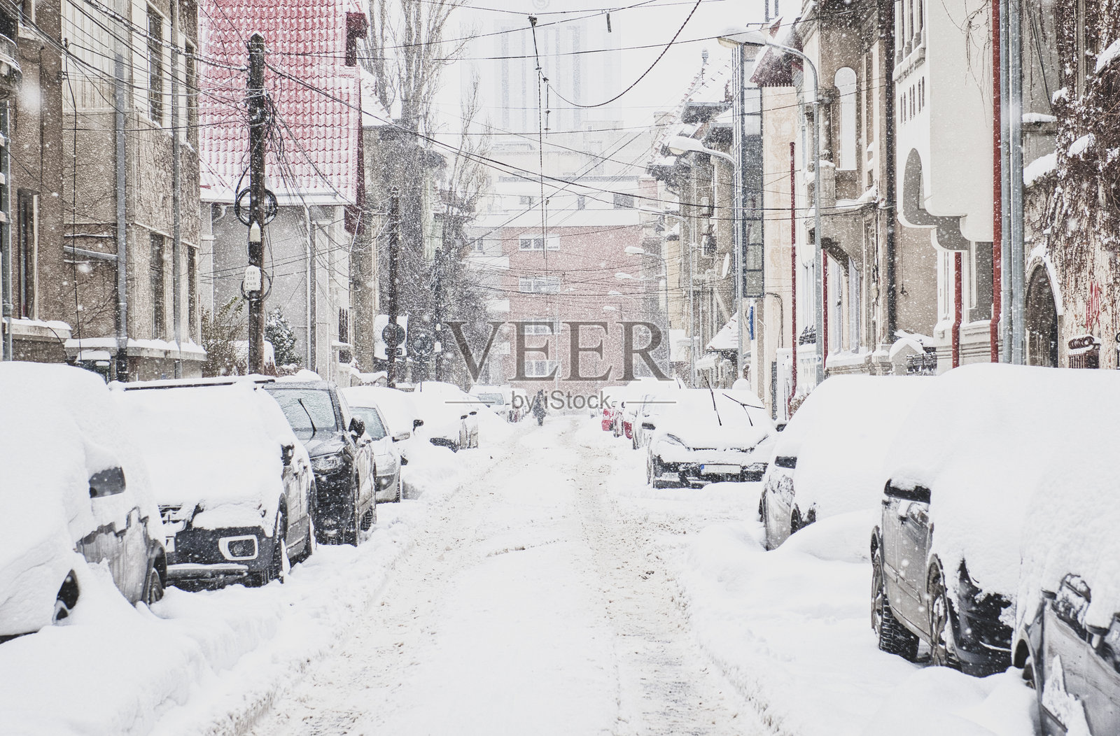 冬季降雪时，雪覆盖的城市街道与停放的汽车照片摄影图片