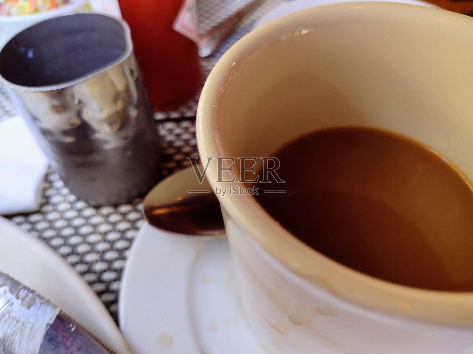 桌子上放着一杯咖啡和一个奶精容器的特写镜头照片摄影图片