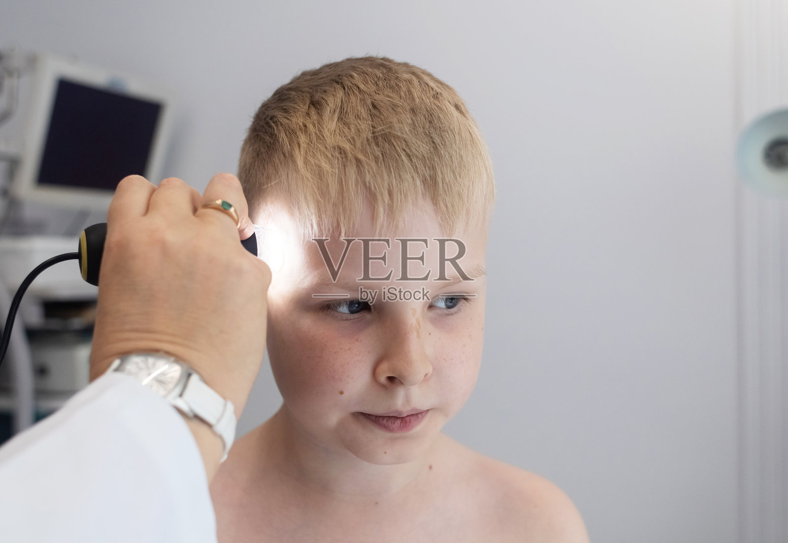 一位儿科皮肤科医生在医疗诊所使用皮肤镜检查小男孩的皮肤。对痣和胎记进行皮肤检查。照片摄影图片