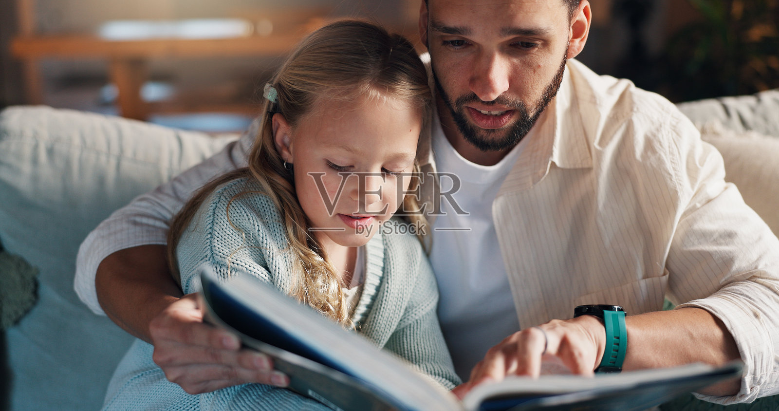 爸爸、女孩和沙发上的书籍，学习与支持发展，爱与亲密在客厅。人们，父亲与孩子在家庭房屋的沙发上共享文学、教育和帮助之手。照片摄影图片