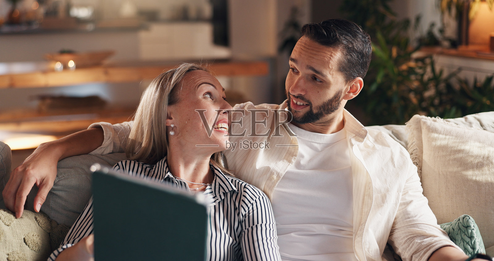 情侣在沙发上使用平板电脑，放松并讨论社交网络上的通知。男女在公寓的休息室里一起看电影、聊天或观看流媒体。照片摄影图片