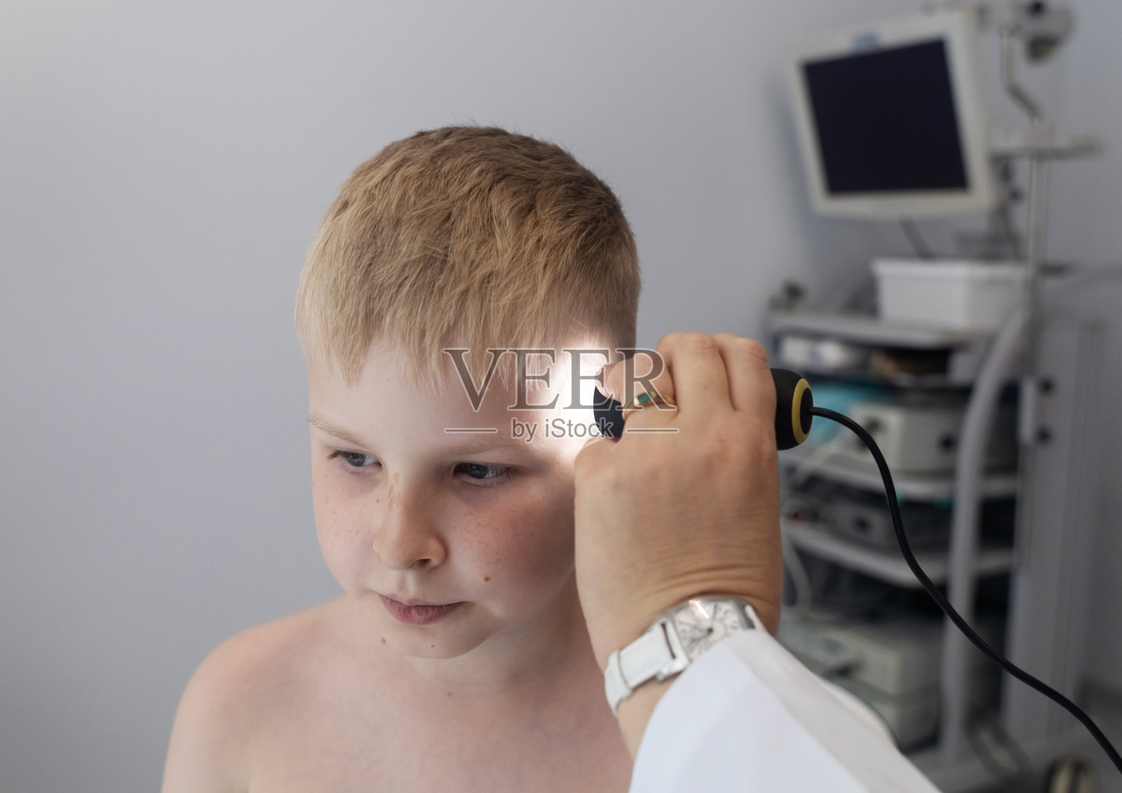 一位儿科皮肤科医生在医疗诊所使用皮肤镜检查小男孩的皮肤，进行痣和胎记的皮肤检查。照片摄影图片