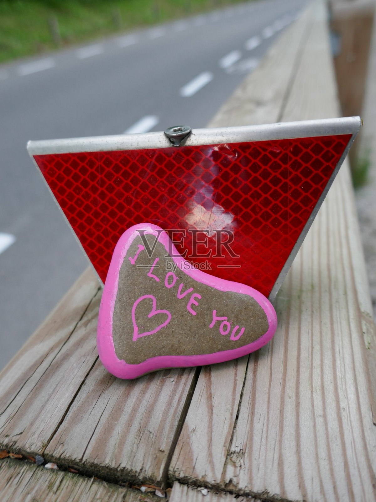 我爱你心形石头靠在路边安全反光器上，竖直照片照片摄影图片