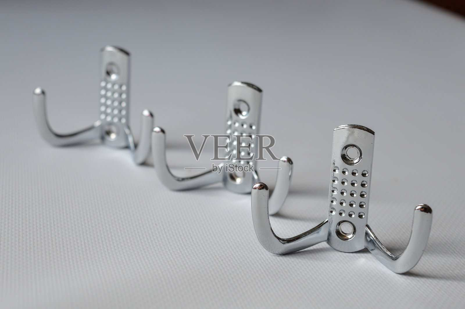 三只金属墙钩排列在白色背景上，适合用于家居储物、组织、极简主义和DIY室内项目的概念。照片摄影图片