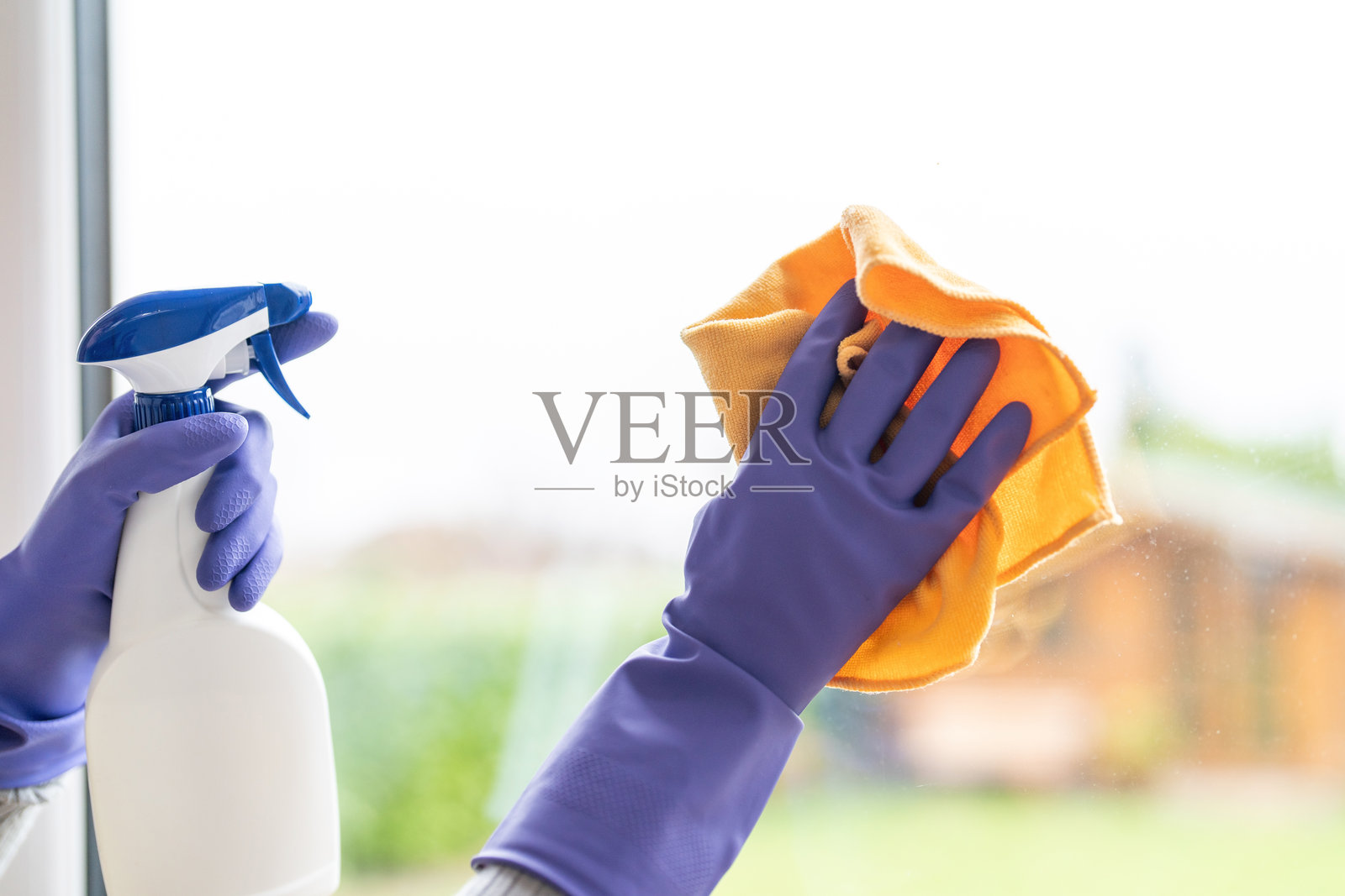 在阳光明媚的日子里，在温馨的家中用喷雾瓶和布清洁窗户照片摄影图片
