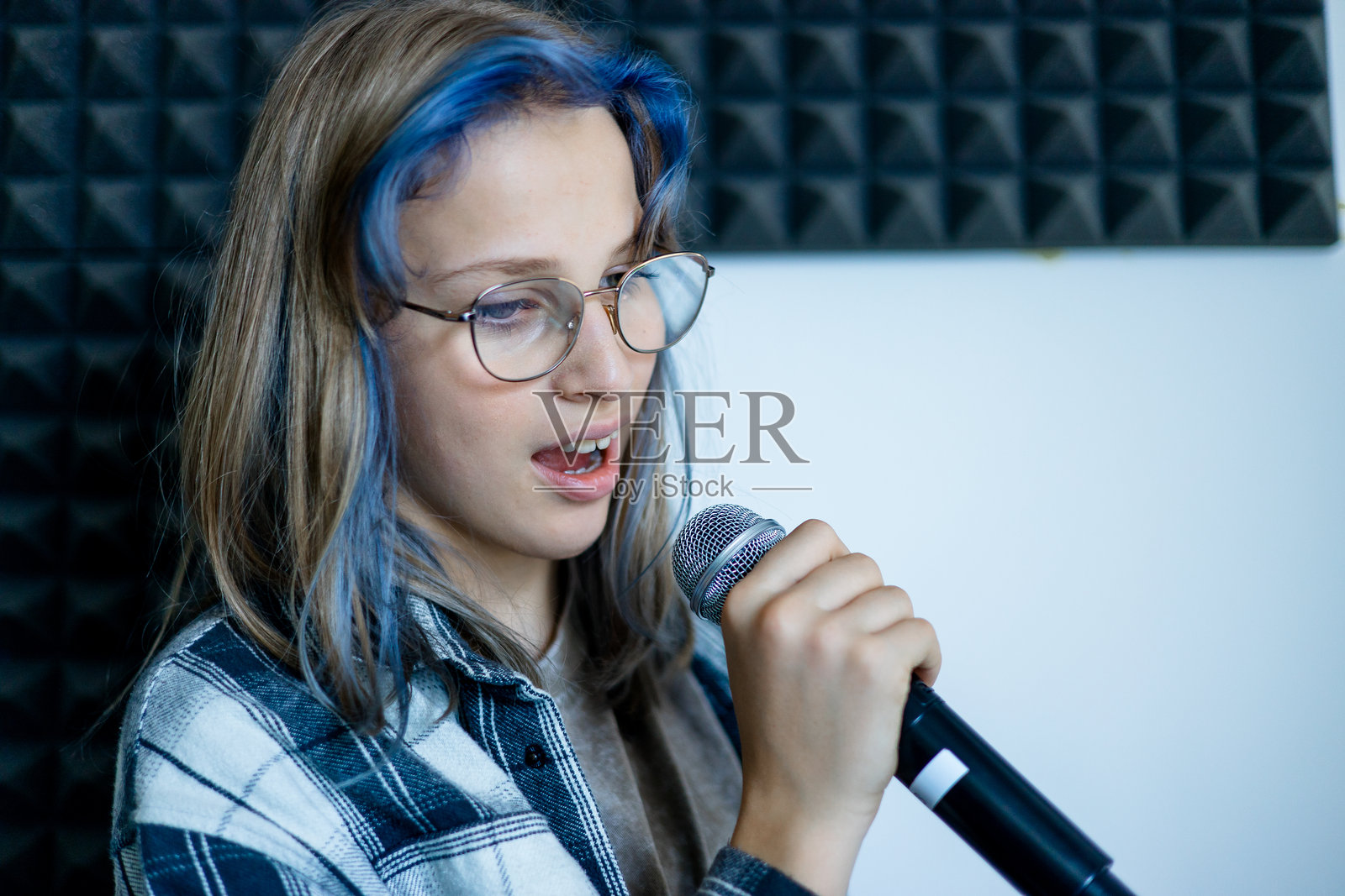 在录音室里用麦克风唱歌的少女照片摄影图片