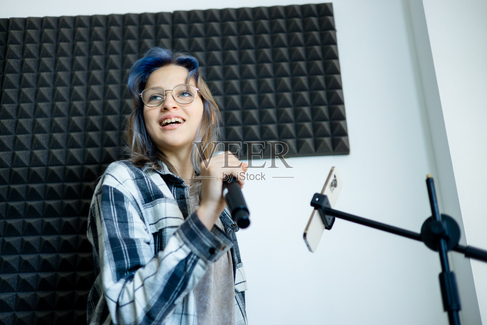青少年女孩在录音室用麦克风唱歌照片摄影图片