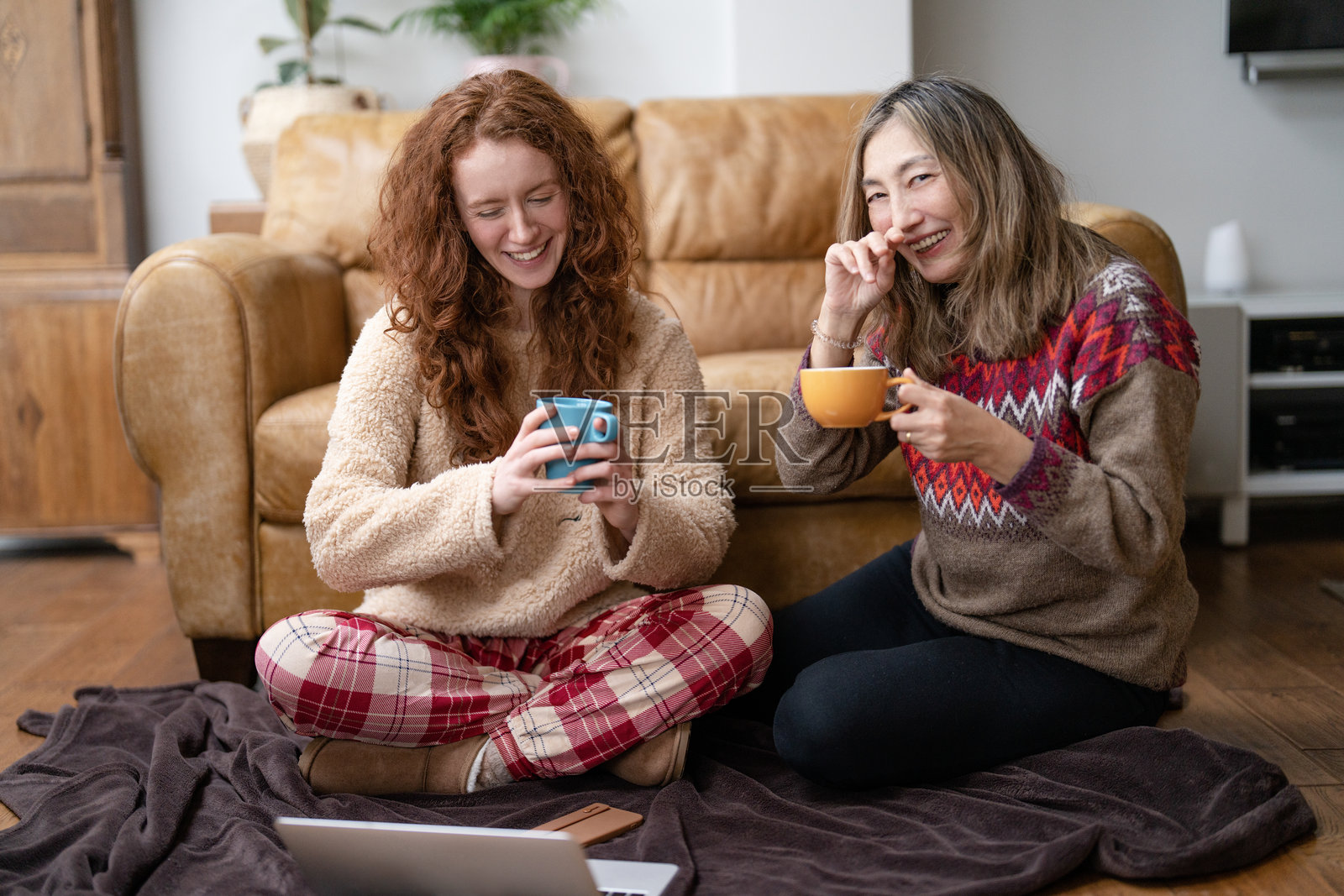 两个朋友在舒适的客厅里享受温暖的饮品和惬意的时光，度过一个轻松的下午聚会。照片摄影图片