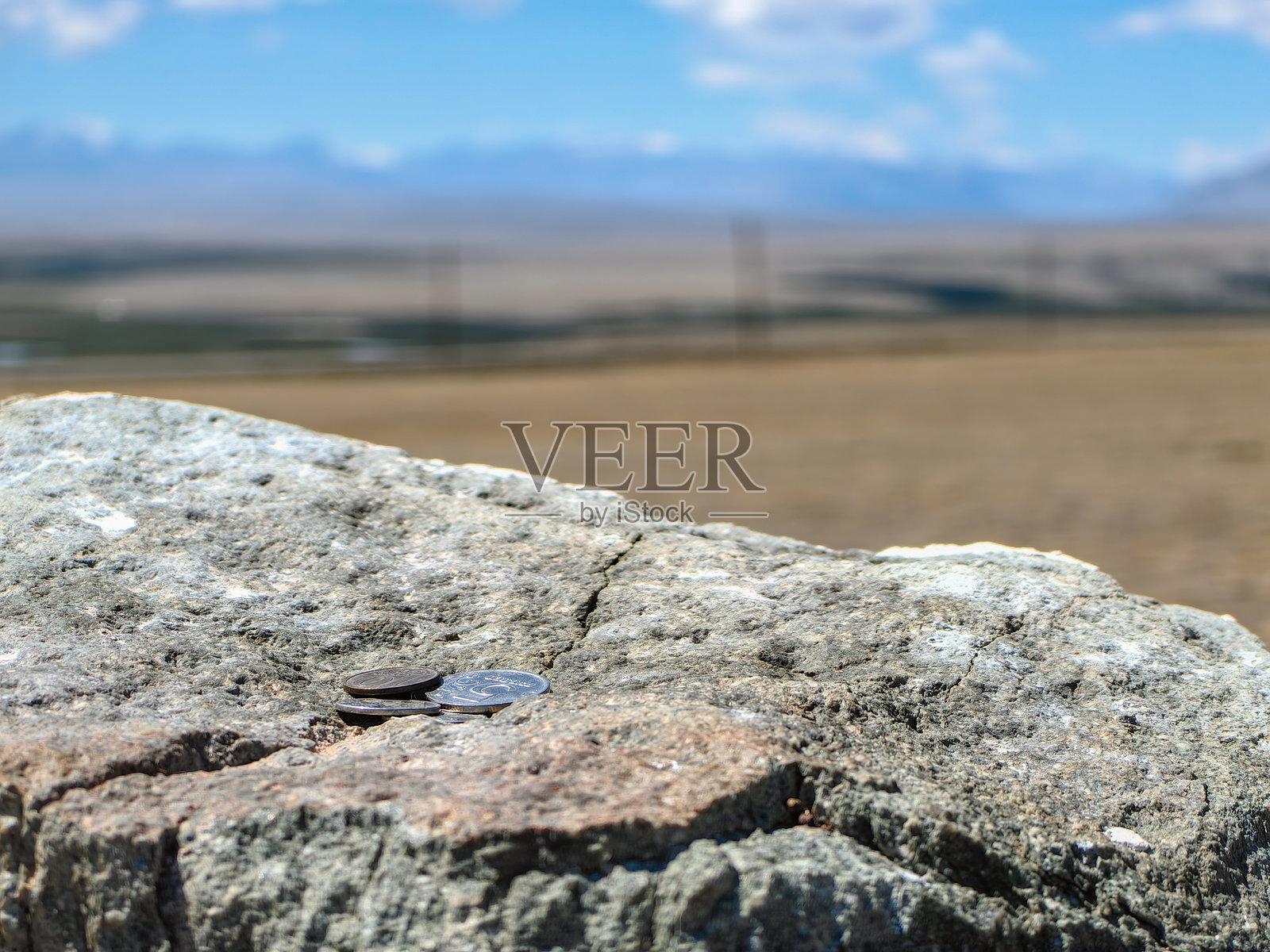 岩石上的硬币，背景是风景如画的山脉景观。照片摄影图片