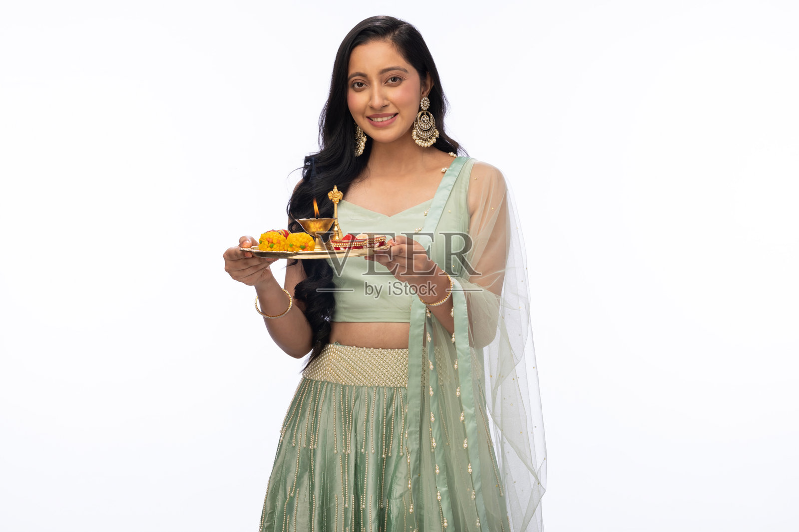 美丽女性在排灯节庆祝中手持祷告托盘，身穿传统服装，背景为白色。照片摄影图片