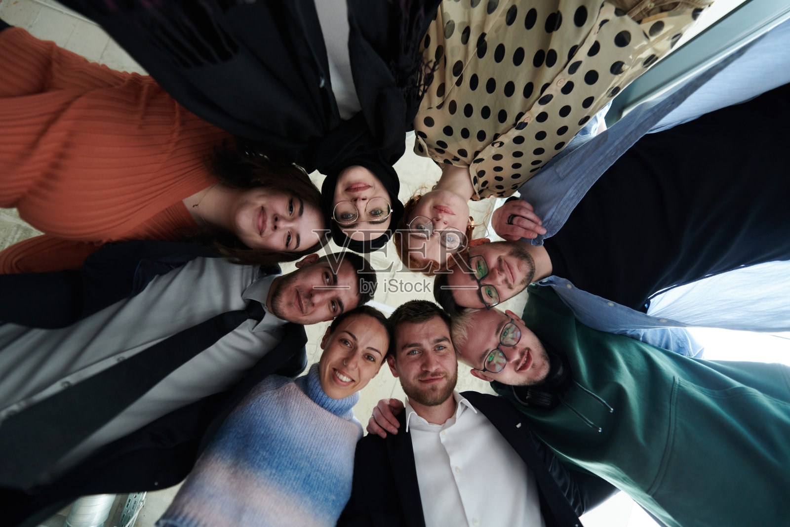 一群多元化的商业专业人士以强大而团结的姿态站在一起，从低角度拍摄，散发出自信和团队合作的气息。照片摄影图片