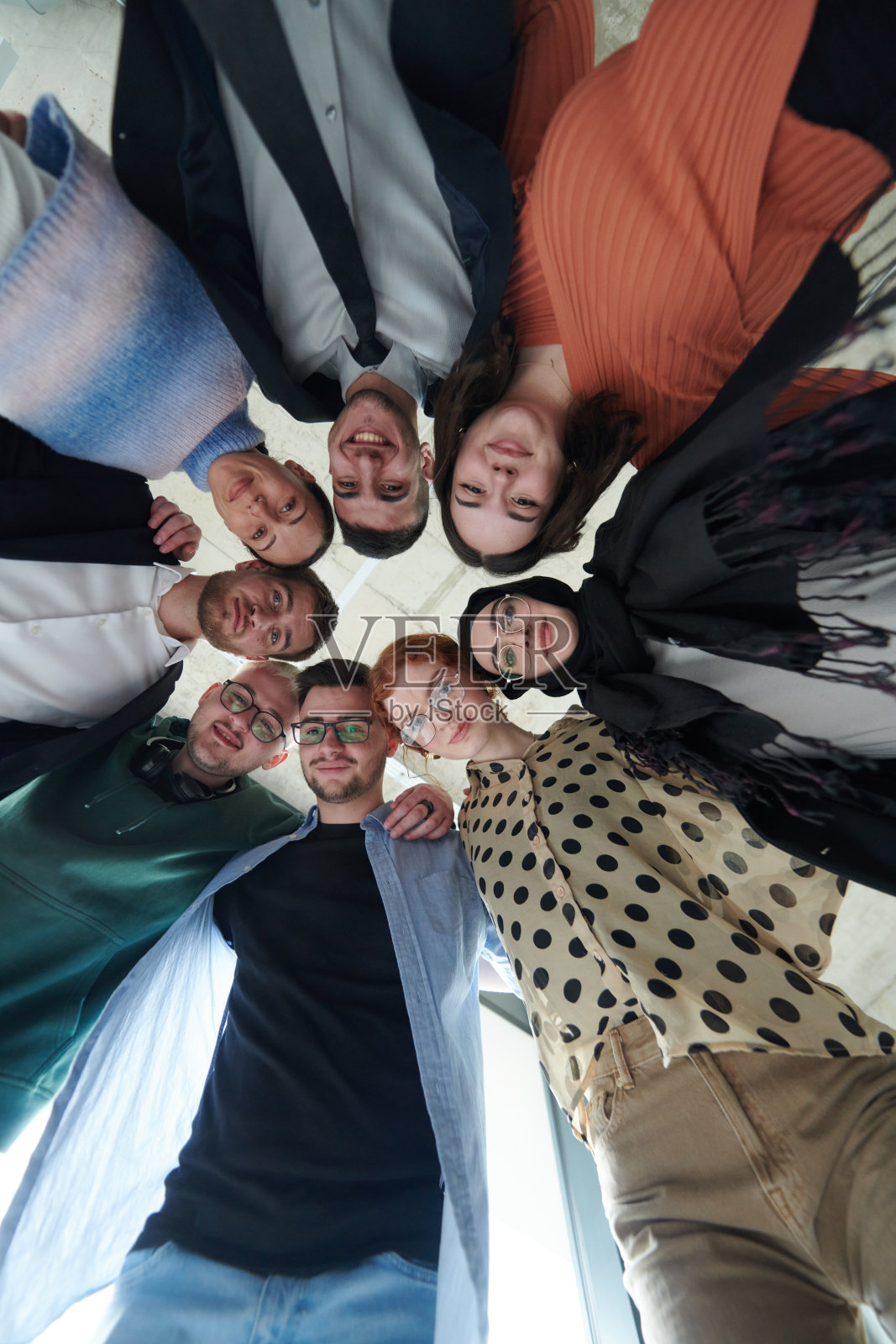 一群多元化的商业专业人士以强大而团结的姿态站在一起，从低角度拍摄，散发出自信和团队合作的气息。照片摄影图片