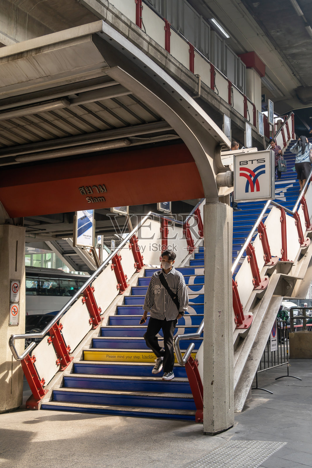 年轻男子在繁忙的城市火车站下蓝色楼梯。休闲通勤者在公共交通设施中穿行。照片摄影图片