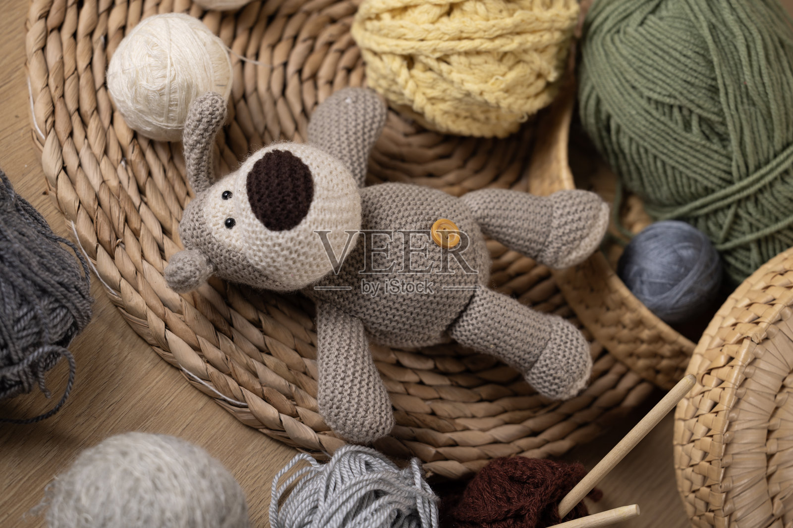 钩针狗玩具被五颜六色的毛线球和针织针围绕照片摄影图片