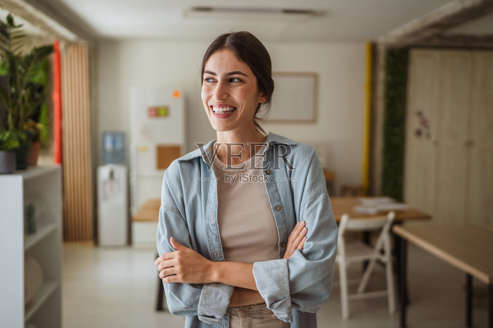 微笑的年轻女商人在现代办公室中双臂交叉的肖像照片摄影图片