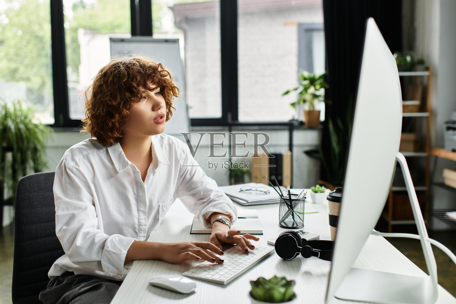 专注的年轻女商人，卷发，在现代办公室中勤奋工作照片摄影图片