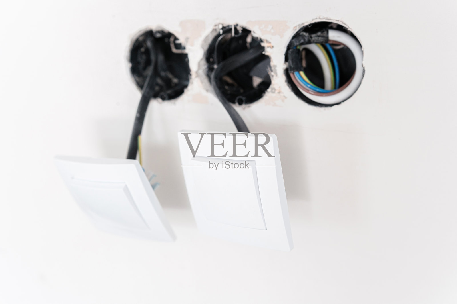 两个白色电灯开关，带有电线，安装在未完成的墙壁上照片摄影图片