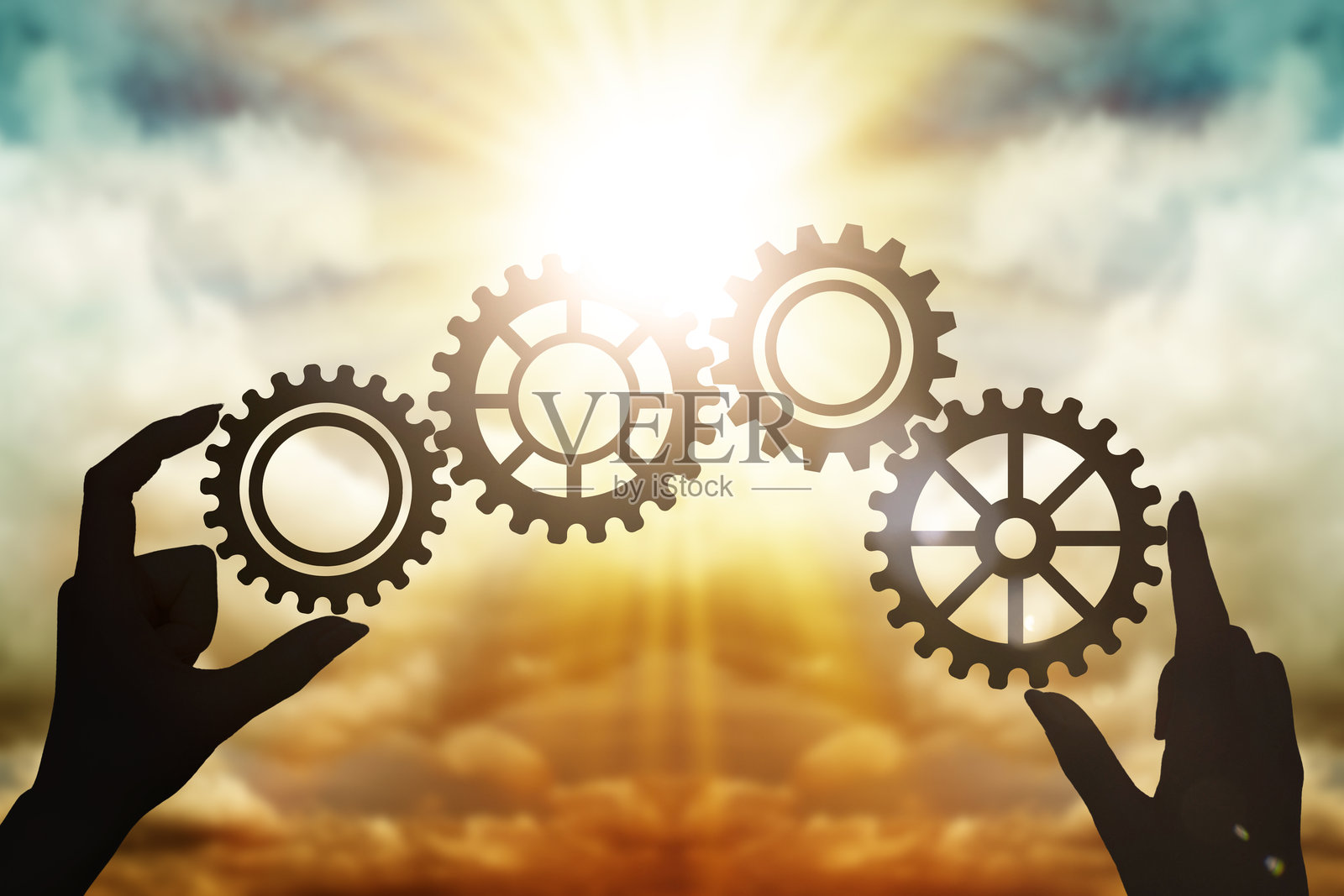 在日落的天空下，手们收集拼图中的齿轮。商业概念，合作伙伴关系，创新，团队合作，协作。照片摄影图片