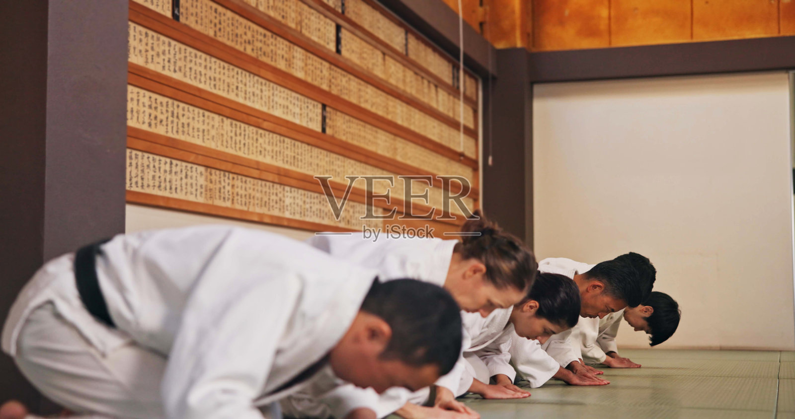 在武术馆中，学生们向师傅行礼，表示尊重，进行练习、训练或自卫课程。文化、空手道以及一群学生向师傅致以问候或礼仪手势，以示敬意。照片摄影图片