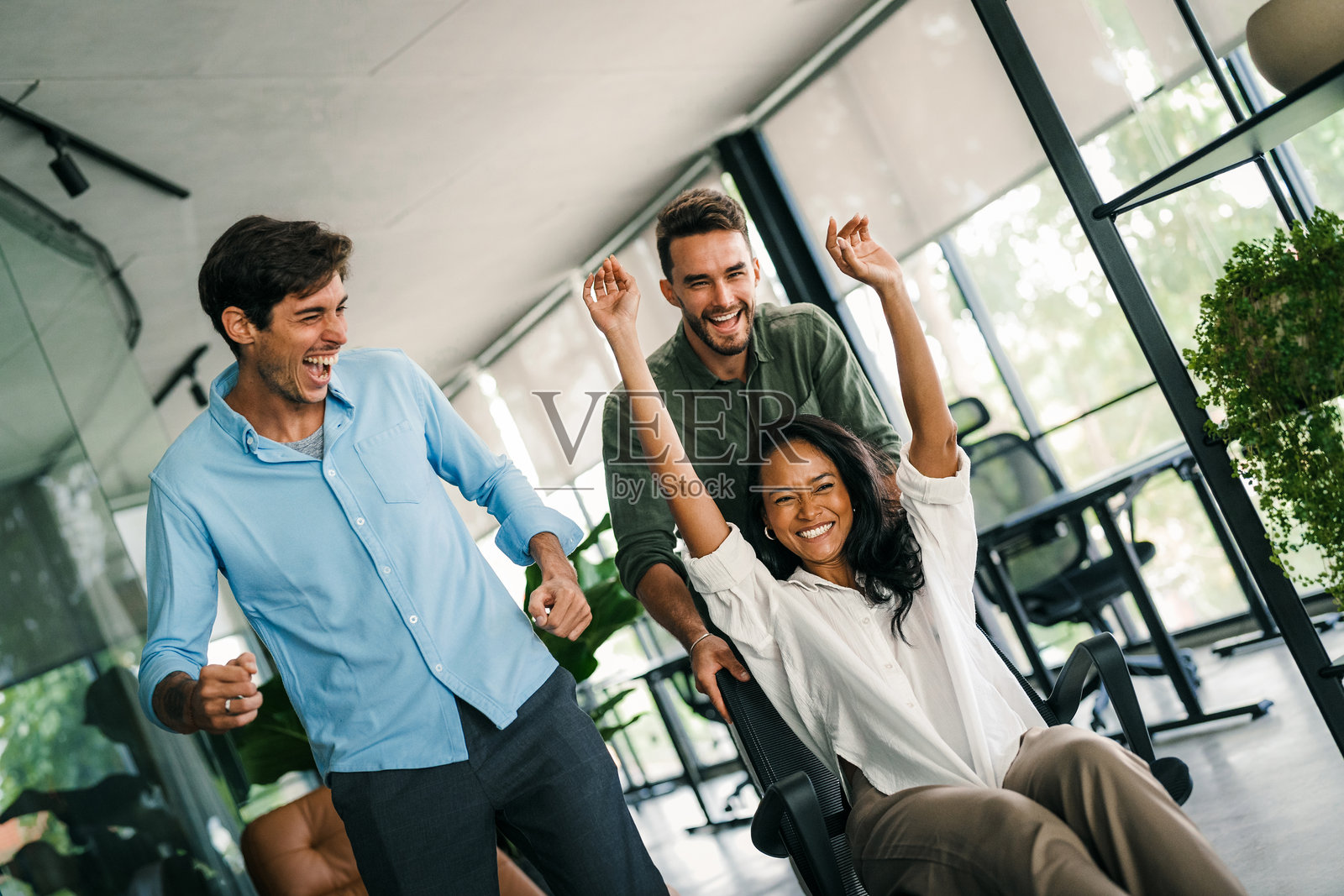 年轻多元化员工在现代创意办公室中欢欣鼓舞的肖像。团队建设照片摄影图片