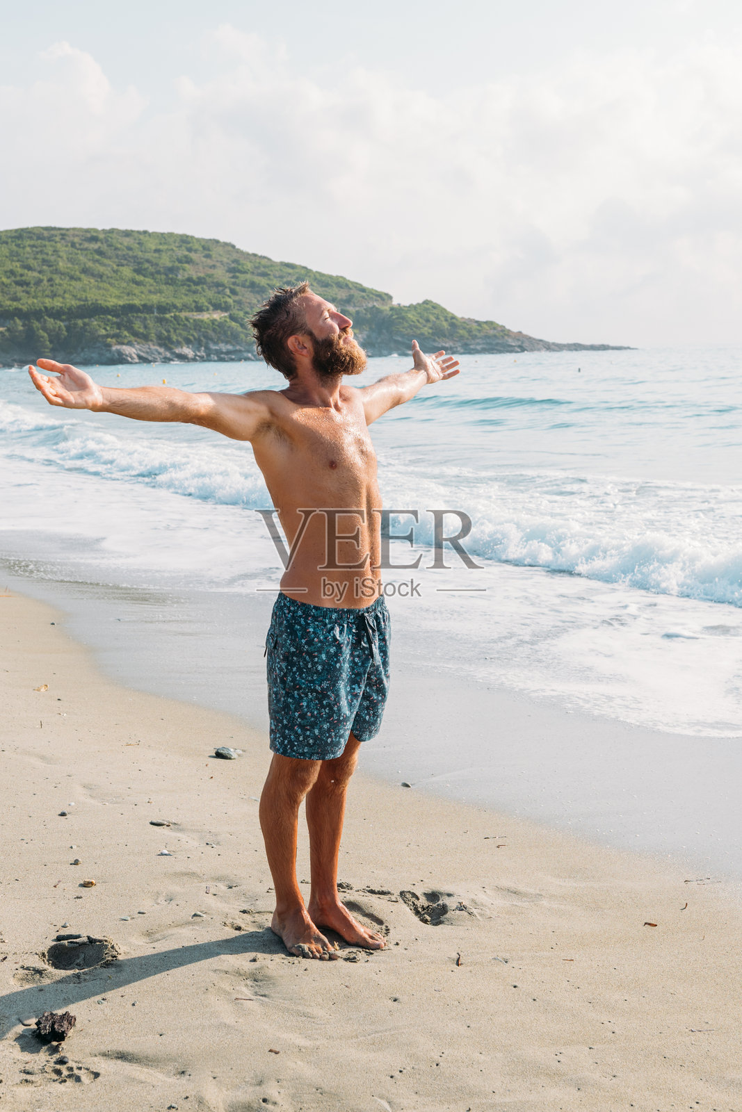 男人在海滩上张开双臂享受清晨时光照片摄影图片