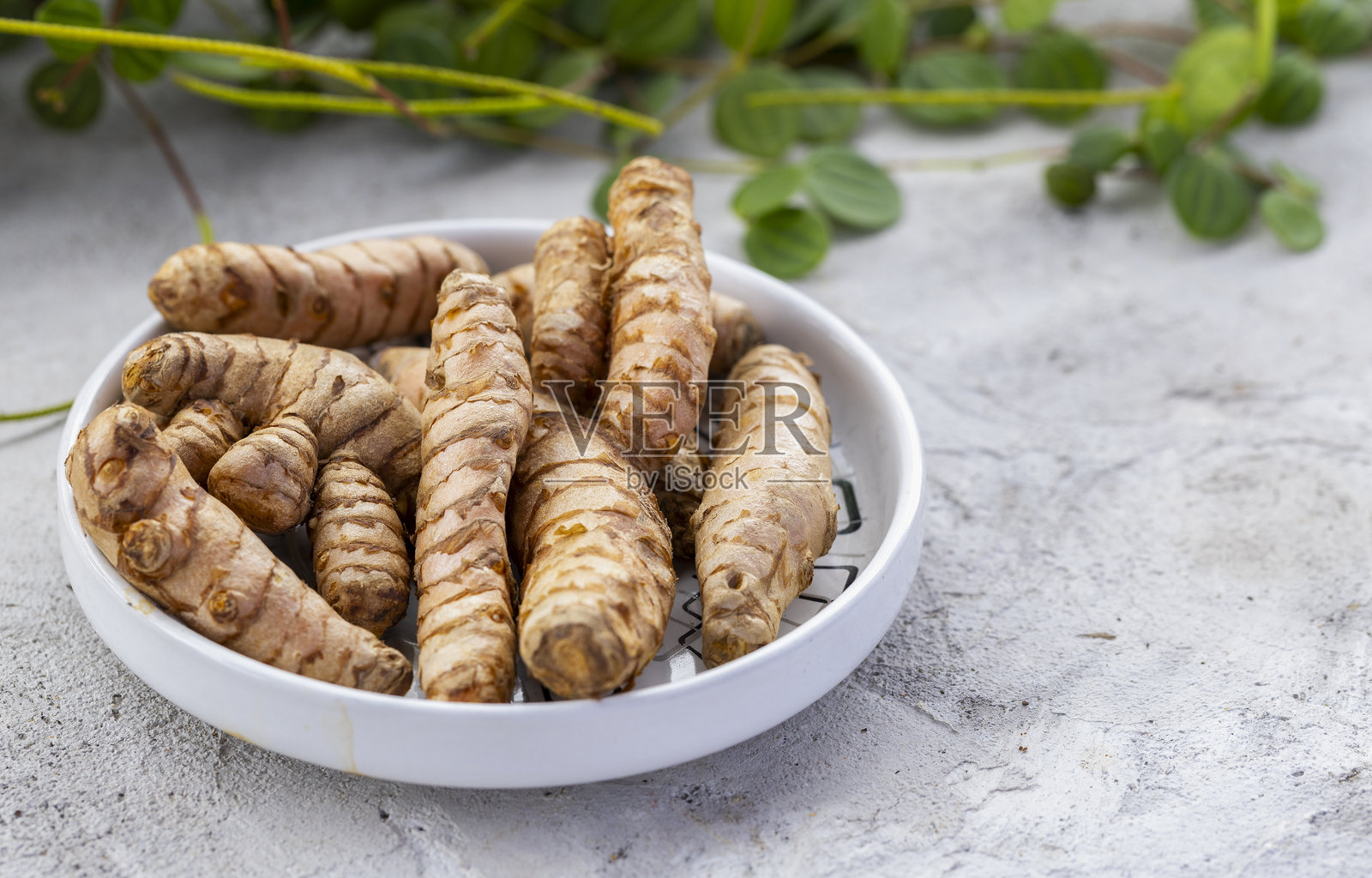 新鲜有机姜黄根放在白色陶瓷碗中照片摄影图片