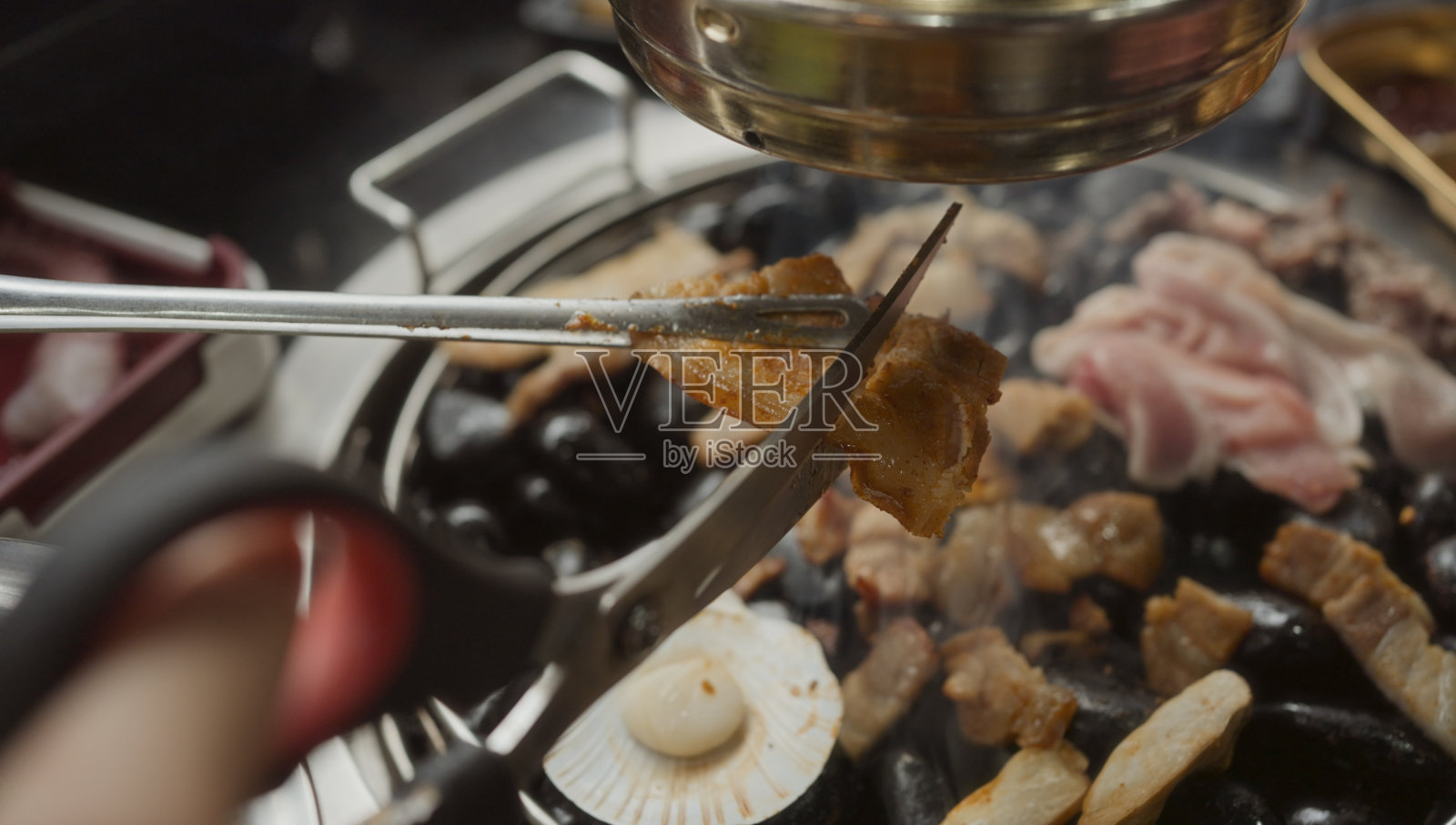 在餐厅的铁烤盘上手工烹饪烟熏烤猪肉。传统韩国风格的炭火烤五花肉牛排。照片摄影图片