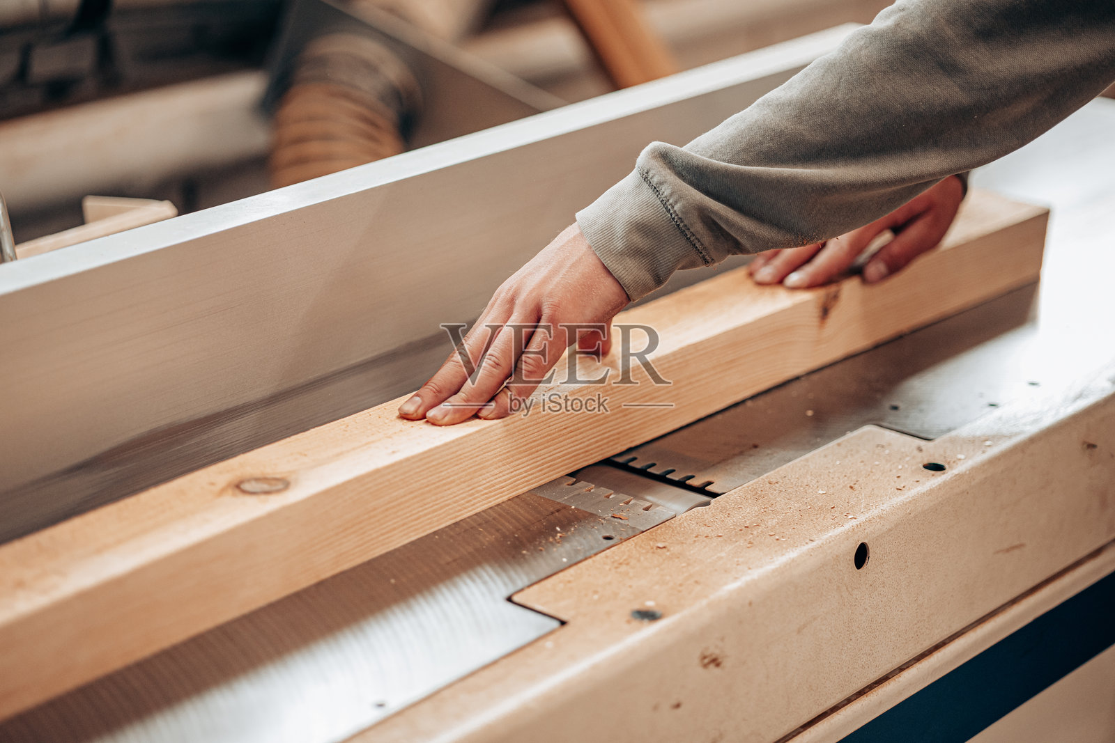 木匠在工作坊中使用台锯切割木梁照片摄影图片