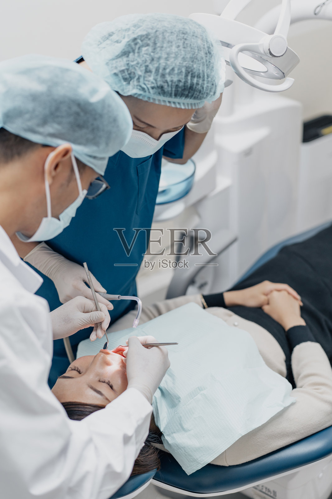 亚洲牙医和助手为女性患者进行口腔护理操作照片摄影图片