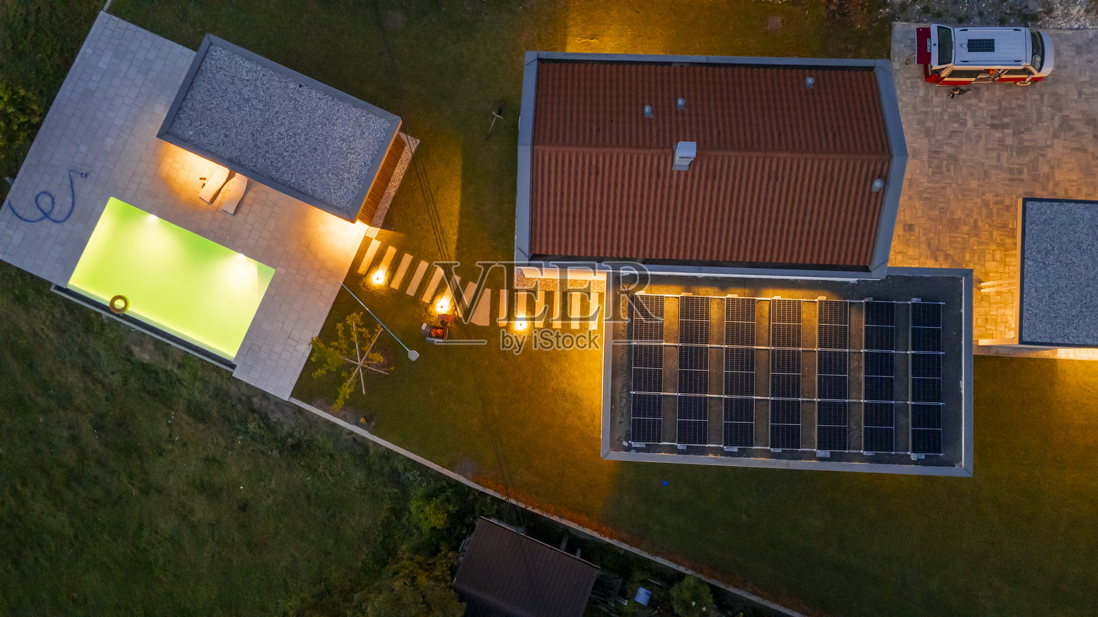 现代自给自足的房屋，蓝色时刻配有太阳能板和温暖的户外照明照片摄影图片