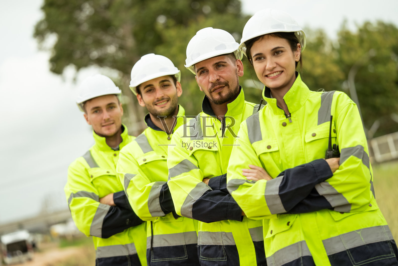 工程师工人双臂交叉，微笑着看向镜头，背景是石油化工行业或炼油厂。照片摄影图片