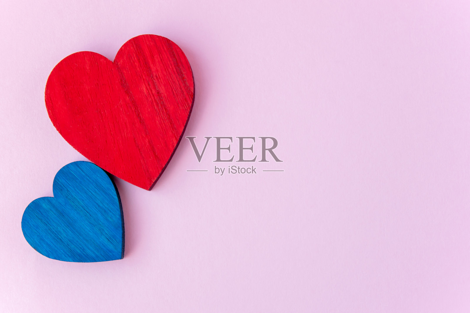 粉色背景上的蓝色和红色木心，留有文字空间。照片摄影图片