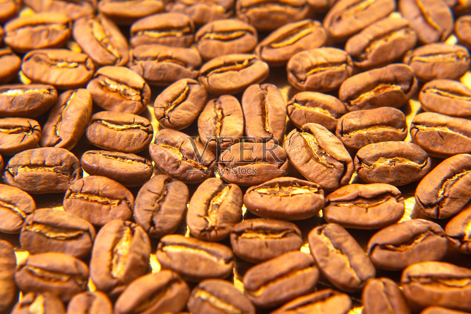 丰富质感的烘焙咖啡豆，带有金色高光，铺展在反光托盘上，适合饮料行业广告。照片摄影图片