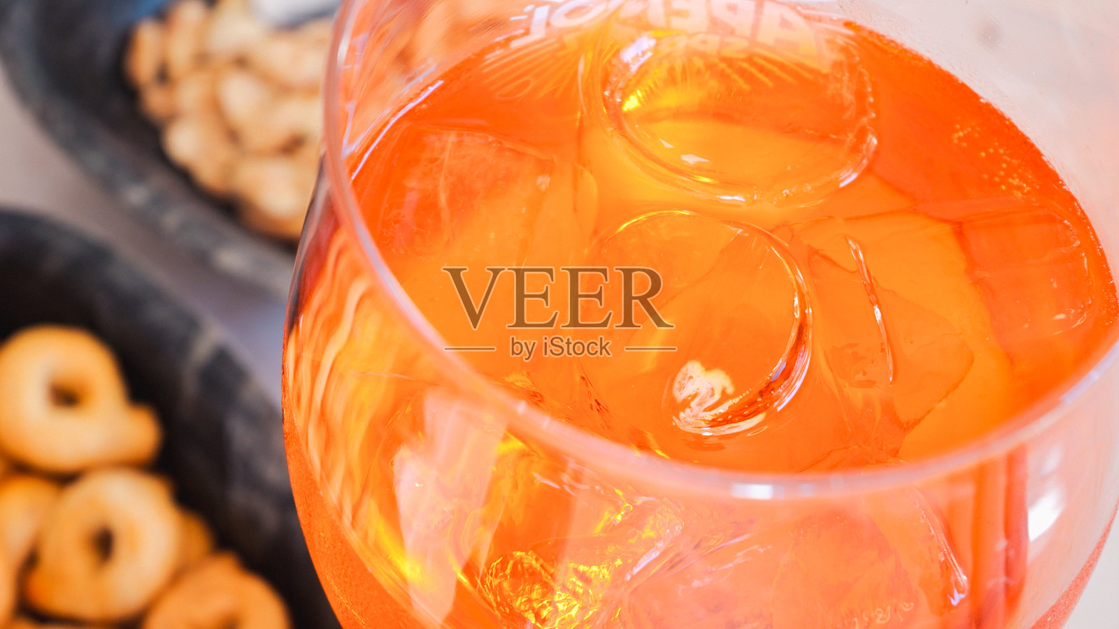 橙色阿佩罗鸡尾酒与闪亮的冰块，静静地放在脆脆的塔拉利饼干旁，捕捉阳光露台上的清新意大利开胃酒时刻照片摄影图片