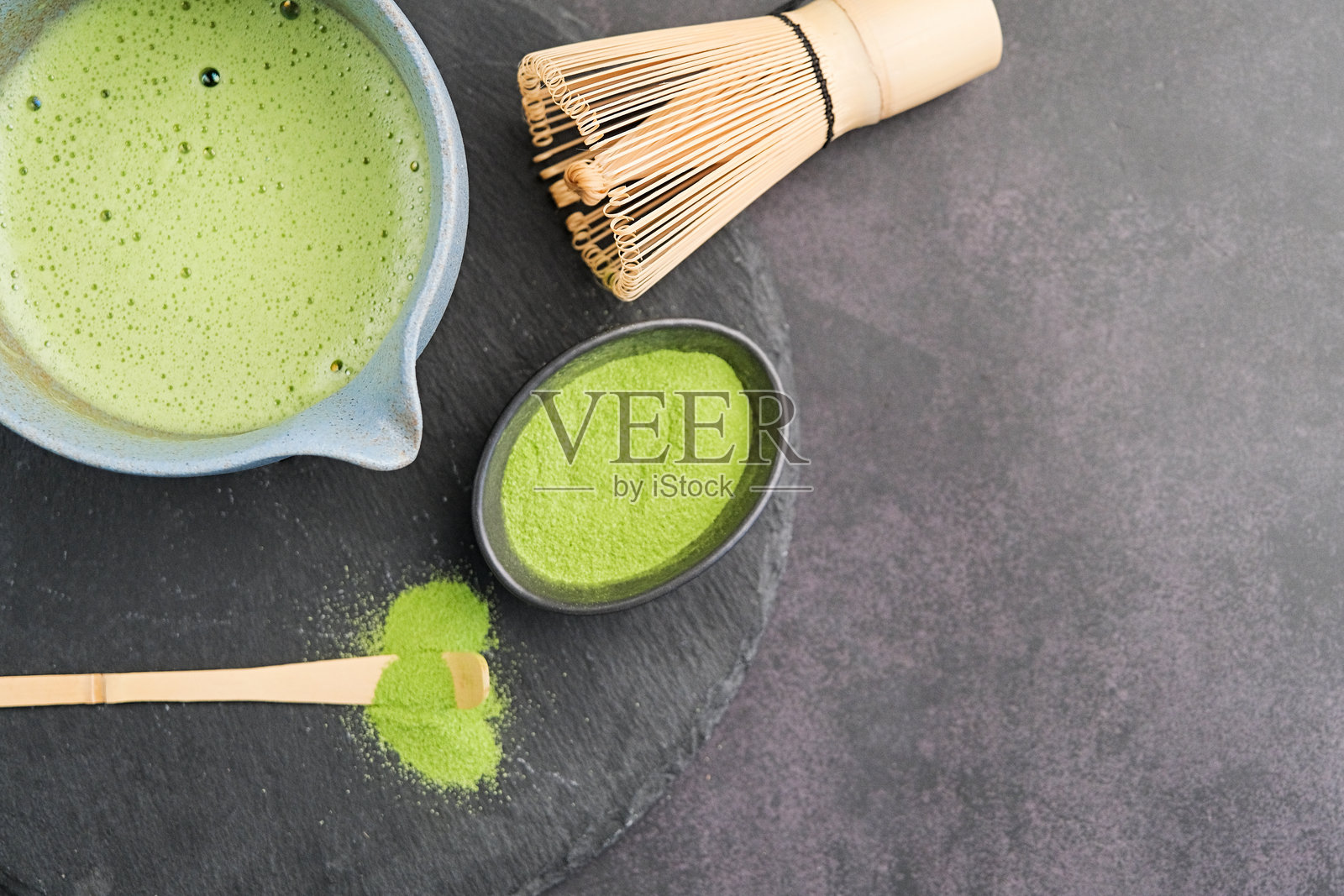 传统绿茶抹茶套装，竹制打泡器和饮品放在石板盘上，深色背景留有空白空间照片摄影图片