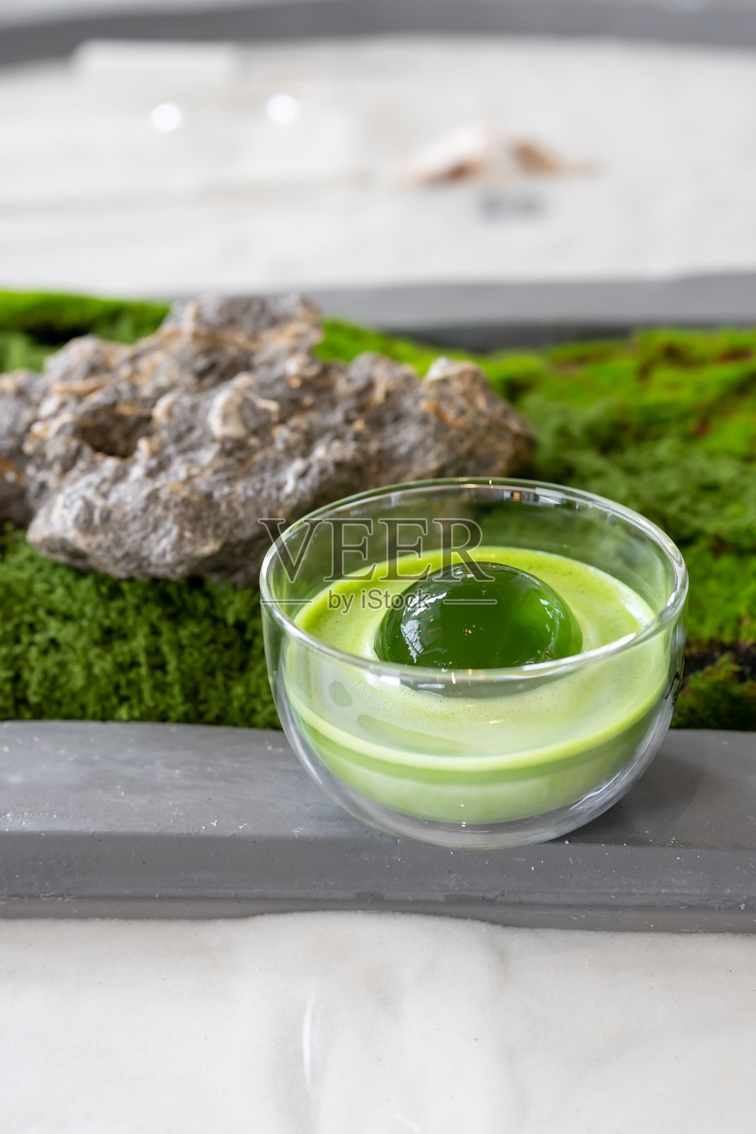 透明玻璃杯中的抹茶或绿茶拿铁，配有圆形冰块，也称为冰球照片摄影图片