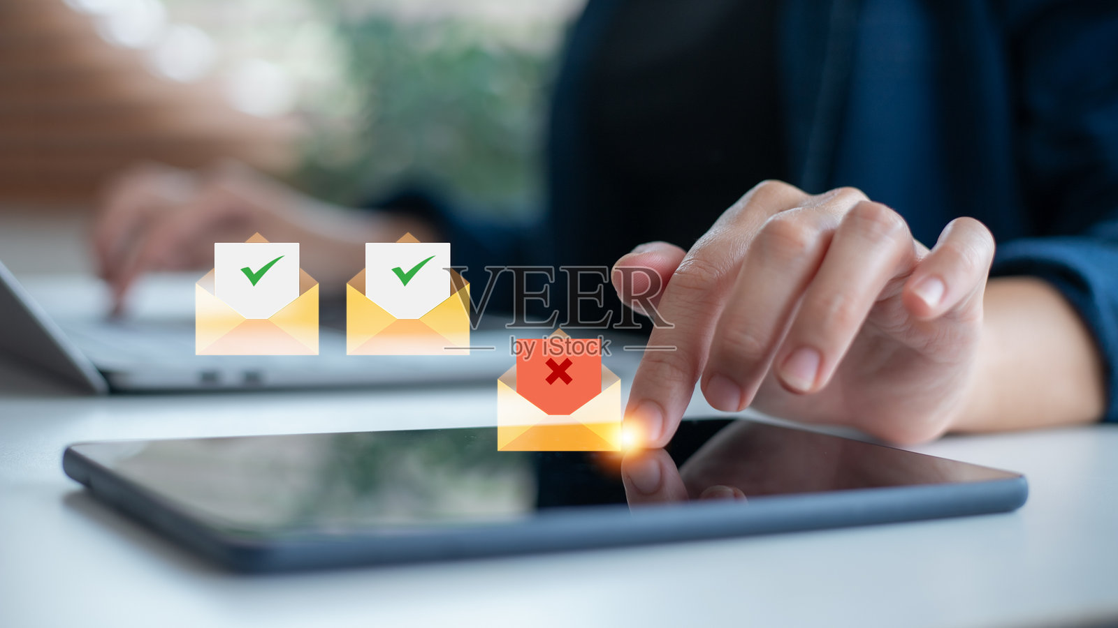 手部特写使用平板电脑，显示带有勾号和叉号的电子邮件图标，代表电子邮件管理、垃圾邮件过滤、消息批准、拒绝和商业中的安全通信。照片摄影图片