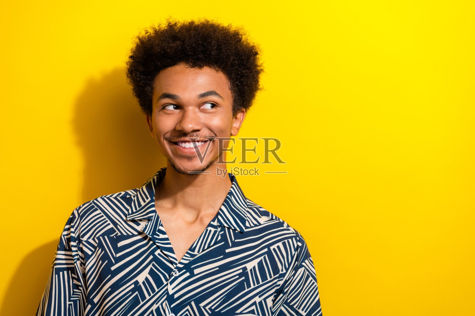 一位英俊年轻男子在充满活力的黄色背景前微笑，穿着休闲服装照片摄影图片