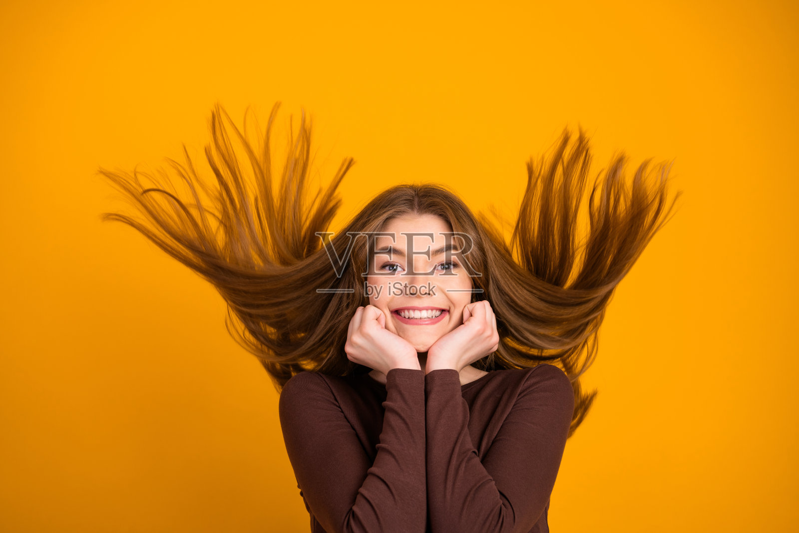 时尚年轻女性在充满活力的黄色背景前微笑，展现出快乐和活力。照片摄影图片