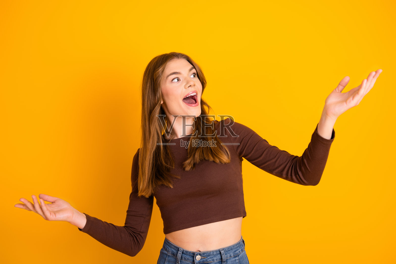 穿着休闲服的年轻女性在充满活力的黄色背景前表达热情和积极性照片摄影图片