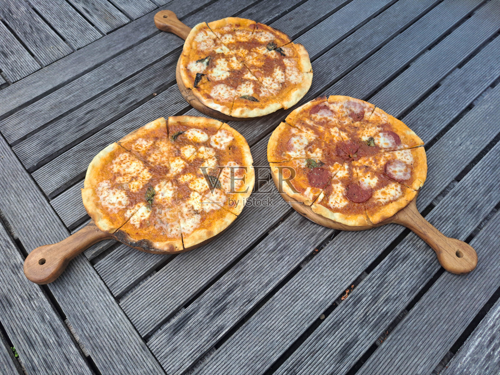 马格丽塔奶酪披萨，配有马苏里拉奶酪、罗勒叶和番茄酱。那不勒斯意大利香肠披萨，配有意大利香肠、马苏里拉奶酪、罗勒叶和番茄酱。奶酪披萨，配有丹麦蓝奶酪、马苏里拉奶酪、帕尔马干酪、菲达奶酪、罗勒叶和番茄酱。照片摄影图片