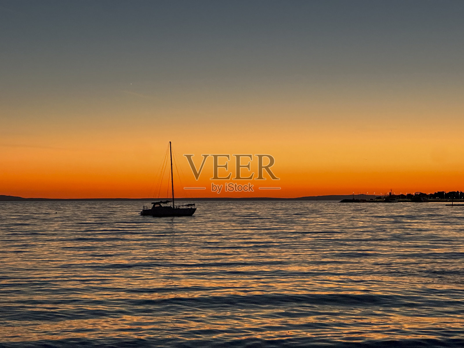 在诺瓦利亚的宁静海面上，帆船在辉煌的日落中航行照片摄影图片