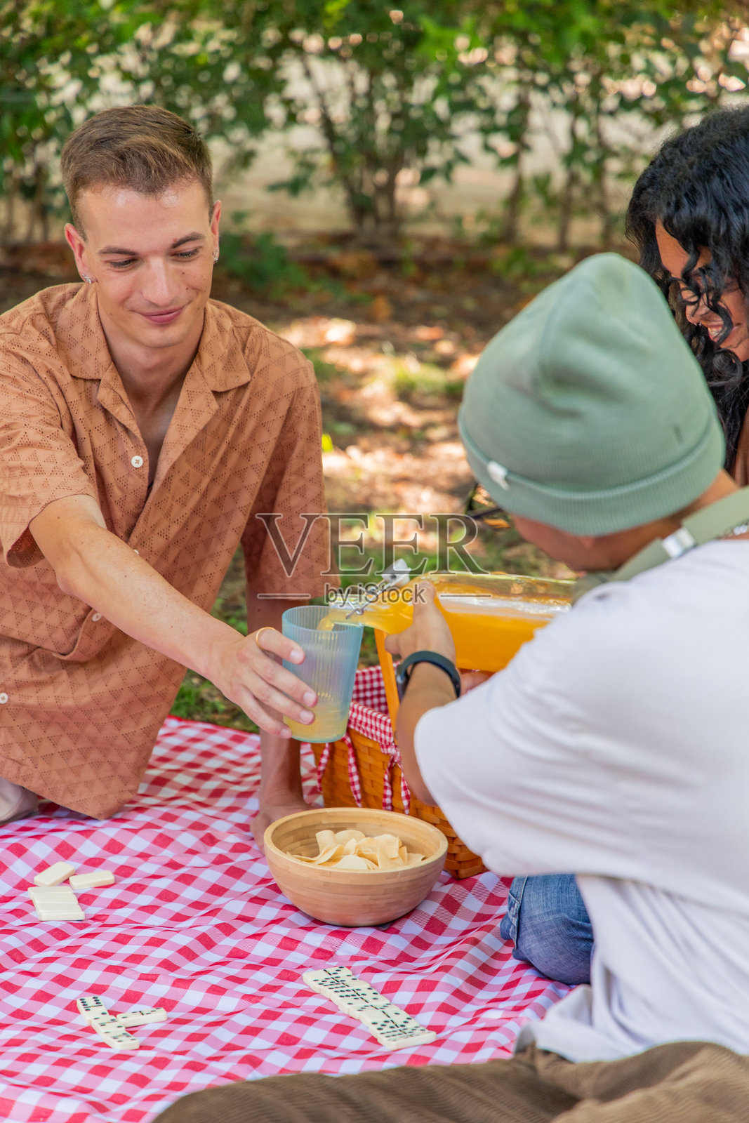 多种族的年轻朋友在公园野餐时倒果汁照片摄影图片